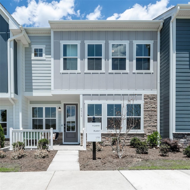 townhome / multi-family property featuring a porch, stone siding, and board and batten siding