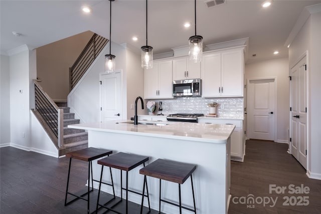 kitchen with a sink, dark wood-type flooring, appliances with stainless steel finishes, and light countertops