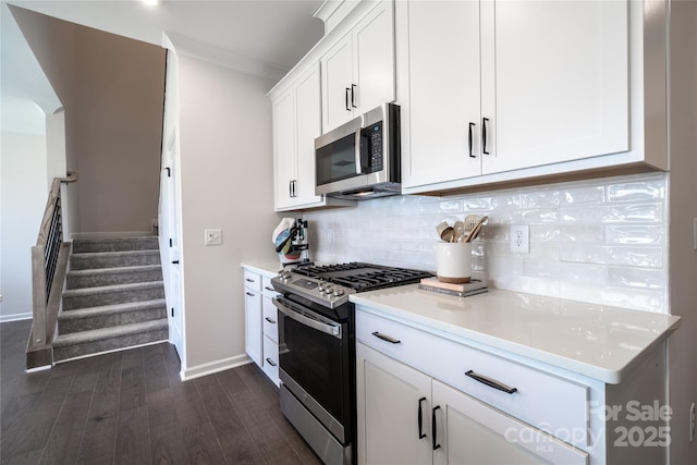 kitchen featuring dark wood-style floors, white cabinetry, appliances with stainless steel finishes, light countertops, and decorative backsplash