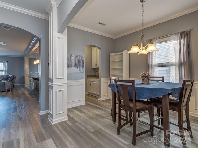 dining space with crown molding, wood-type flooring, and an inviting chandelier