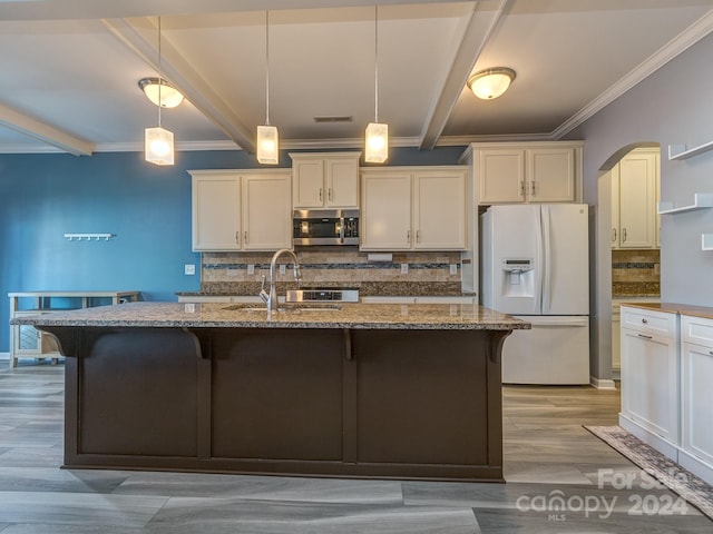 kitchen with pendant lighting, stone countertops, and white refrigerator with ice dispenser