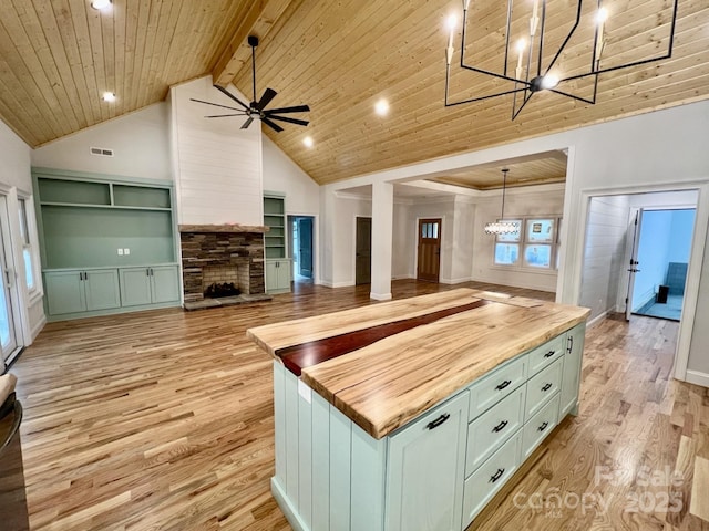 kitchen with a fireplace, butcher block countertops, decorative light fixtures, wood ceiling, and light wood-type flooring