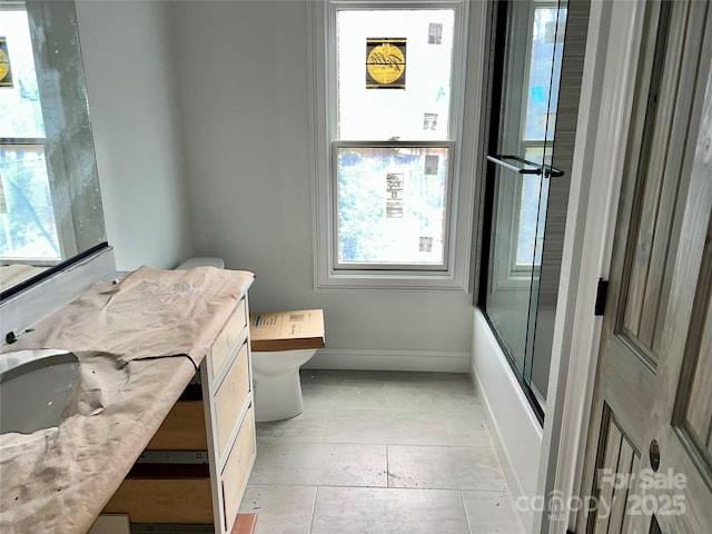 full bathroom with enclosed tub / shower combo, vanity, and toilet