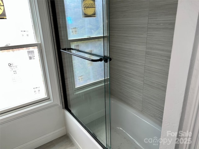 bathroom featuring combined bath / shower with glass door