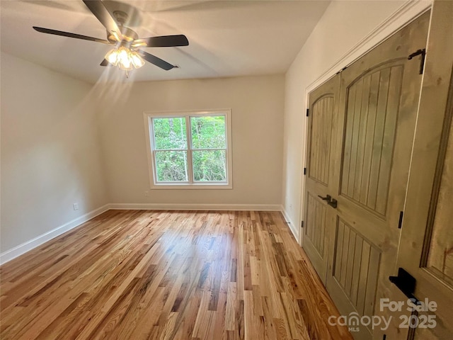 spare room featuring light wood finished floors, baseboards, and ceiling fan