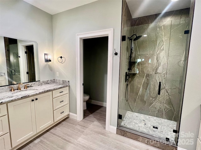 full bath with a marble finish shower, toilet, vanity, baseboards, and wood finished floors