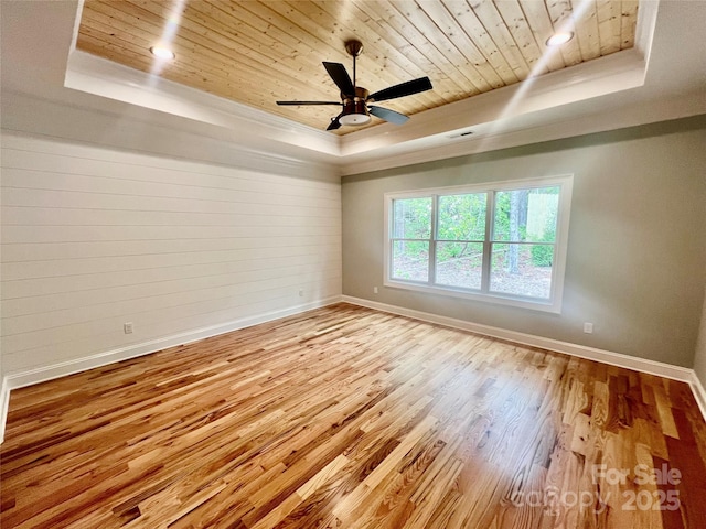 spare room featuring a tray ceiling, wood ceiling, baseboards, wood finished floors, and a ceiling fan