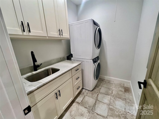 clothes washing area featuring estacked washer and dryer, cabinet space, baseboards, and light stone finish flooring