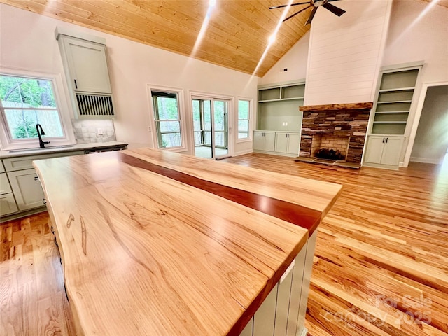 unfurnished living room with a sink, a ceiling fan, light wood-type flooring, wood ceiling, and plenty of natural light