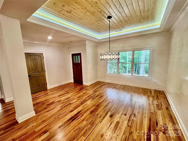 spare room with crown molding, a tray ceiling, wood ceiling, wood finished floors, and baseboards