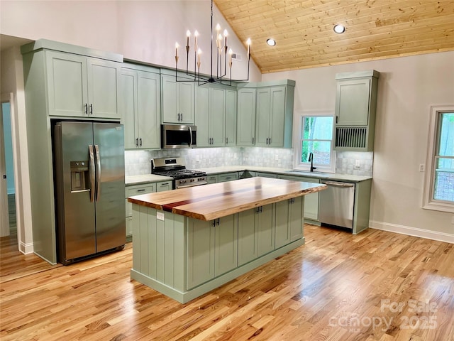 kitchen with appliances with stainless steel finishes, wooden counters, wooden ceiling, lofted ceiling, and a kitchen island