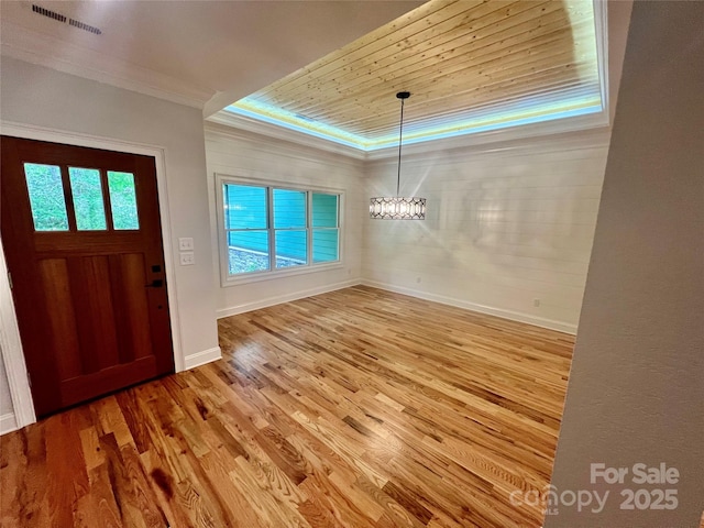 foyer featuring wood finished floors, a chandelier, baseboards, crown molding, and wooden ceiling