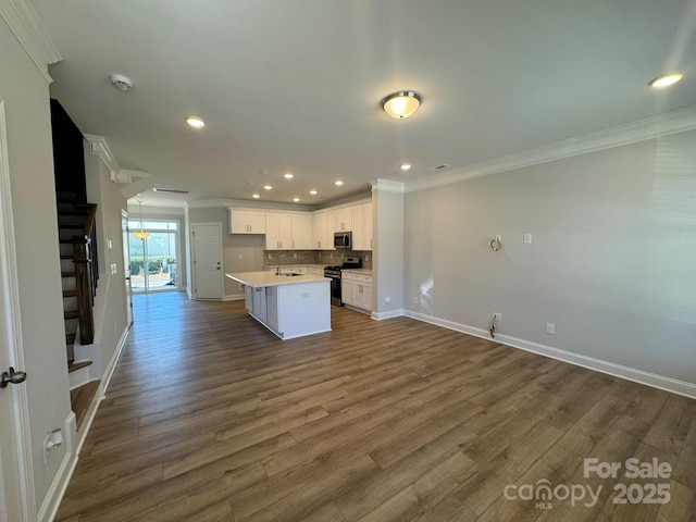 kitchen featuring white cabinets, a kitchen island, open floor plan, stainless steel appliances, and light countertops