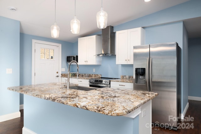 kitchen featuring white cabinetry, wall chimney exhaust hood, an island with sink, and appliances with stainless steel finishes