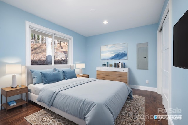 bedroom with dark hardwood / wood-style flooring, electric panel, and a closet