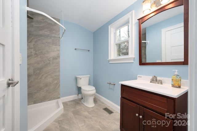 bathroom featuring tile patterned floors, lofted ceiling, tiled shower, toilet, and vanity