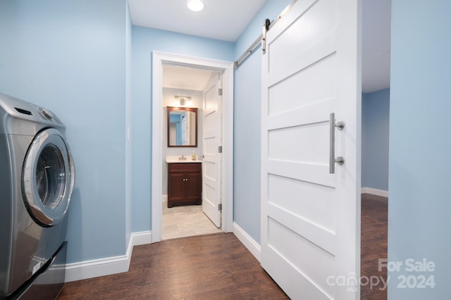 washroom with hardwood / wood-style flooring, a barn door, and washer / clothes dryer