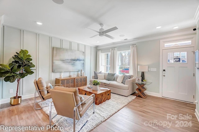 living room featuring ceiling fan, crown molding, and light hardwood / wood-style flooring