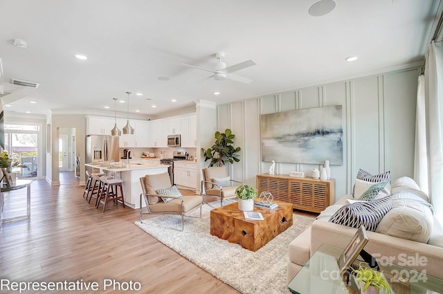 living room featuring ceiling fan, crown molding, and light hardwood / wood-style flooring