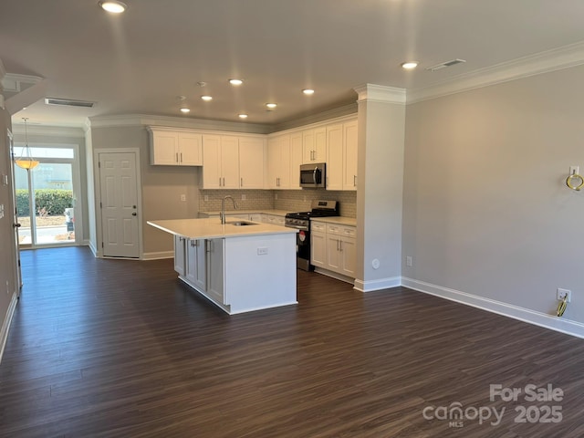 kitchen featuring appliances with stainless steel finishes, white cabinets, light countertops, and a center island with sink