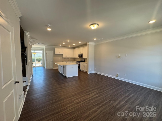 kitchen with white cabinets, open floor plan, light countertops, appliances with stainless steel finishes, and an island with sink