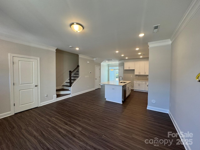 kitchen featuring an island with sink, open floor plan, light countertops, white cabinetry, and a sink