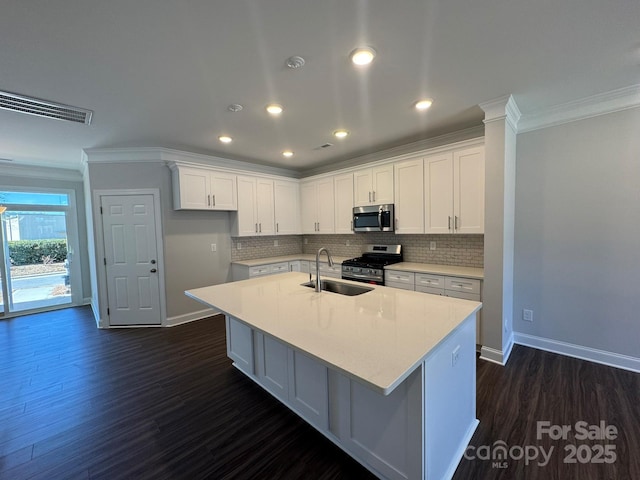 kitchen featuring a center island with sink, stainless steel appliances, visible vents, white cabinetry, and a sink