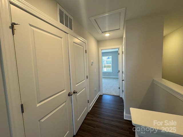 corridor featuring dark wood-style floors, visible vents, and baseboards