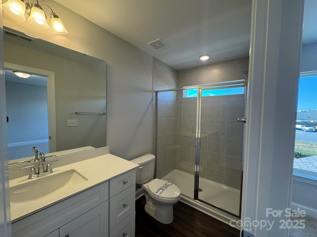 bathroom with a stall shower, visible vents, vanity, and toilet