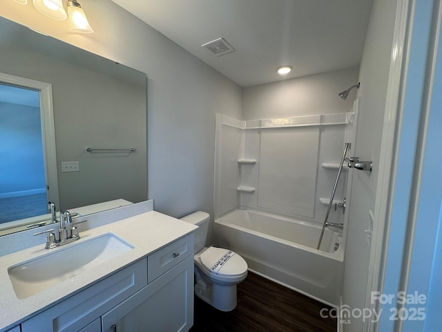 bathroom featuring visible vents, shower / bathing tub combination, toilet, vanity, and wood finished floors