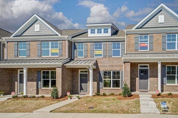 view of front of property featuring metal roof, a standing seam roof, and brick siding