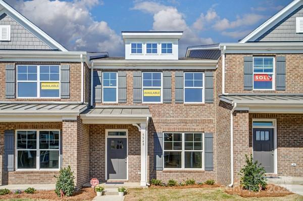 townhome / multi-family property with metal roof, a standing seam roof, and brick siding