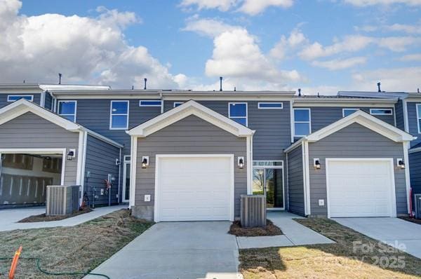 townhome / multi-family property with central AC unit, driveway, and a garage