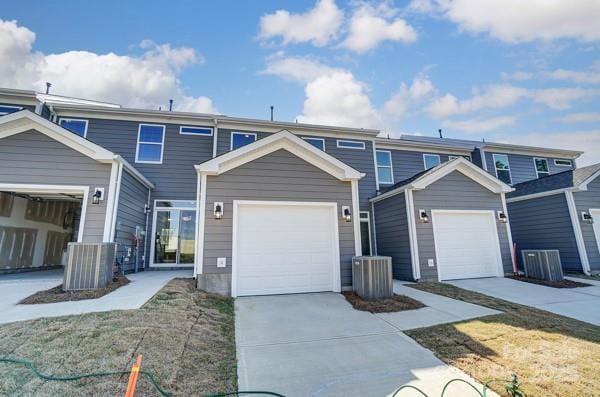 view of front facade featuring driveway, a garage, and cooling unit