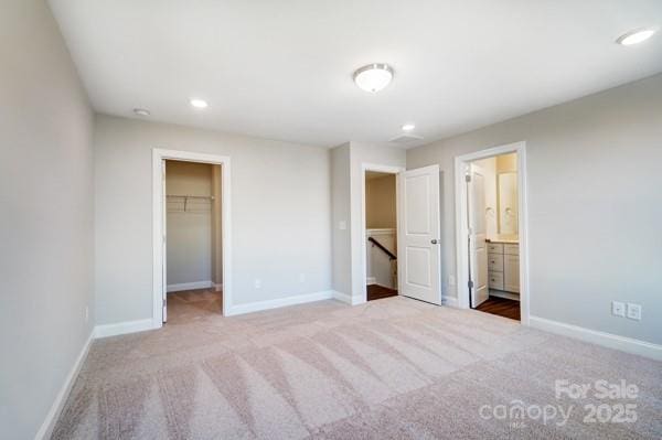 unfurnished bedroom featuring a walk in closet, baseboards, and recessed lighting