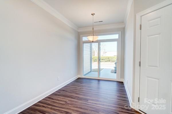 interior space featuring baseboards, visible vents, crown molding, and dark wood-style floors