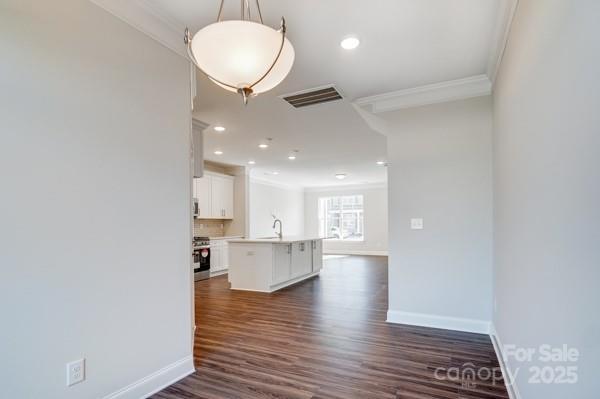 interior space featuring visible vents, crown molding, baseboards, stainless steel range oven, and a sink