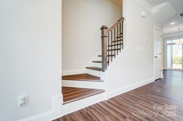 stairs featuring baseboards, visible vents, ornamental molding, and wood finished floors