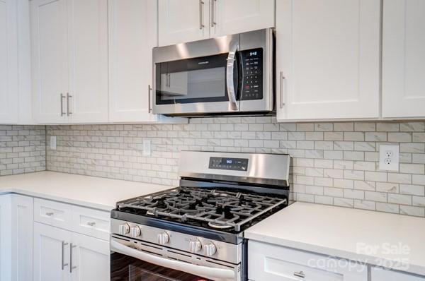 kitchen with white cabinetry, light countertops, backsplash, and stainless steel appliances