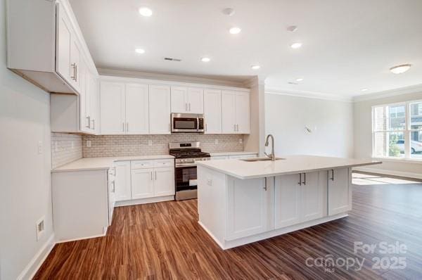 kitchen with light countertops, ornamental molding, stainless steel appliances, dark wood finished floors, and a sink