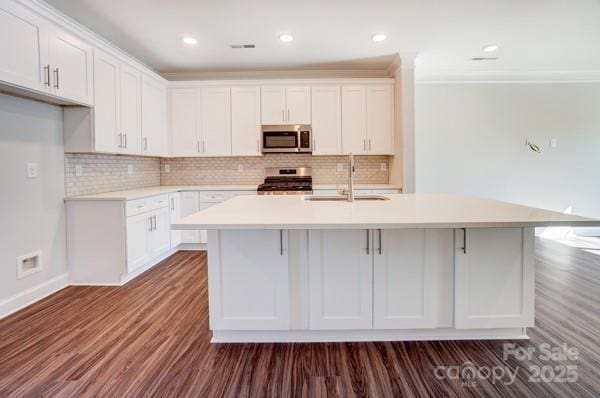 kitchen with a sink, white cabinetry, appliances with stainless steel finishes, dark wood finished floors, and a kitchen island with sink