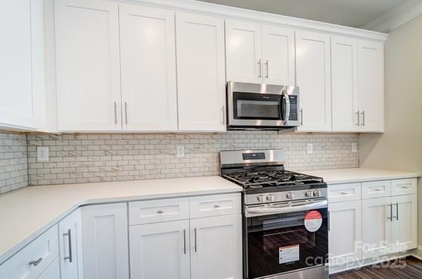 kitchen with white cabinetry, backsplash, light countertops, and appliances with stainless steel finishes