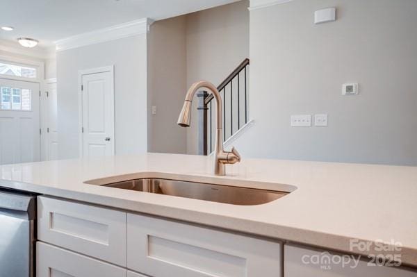 kitchen featuring light countertops, a sink, stainless steel dishwasher, and crown molding