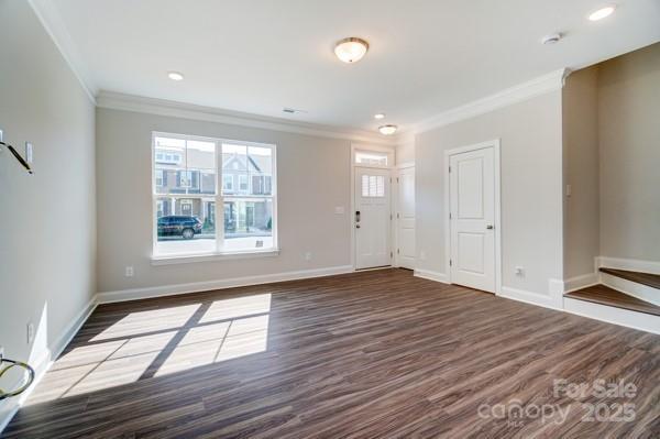 unfurnished living room featuring baseboards, recessed lighting, ornamental molding, and dark wood-type flooring