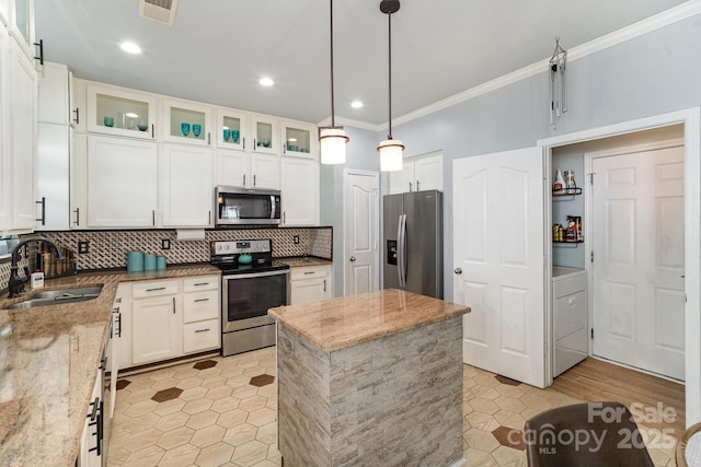 kitchen with stainless steel appliances, a sink, light stone counters, glass insert cabinets, and pendant lighting