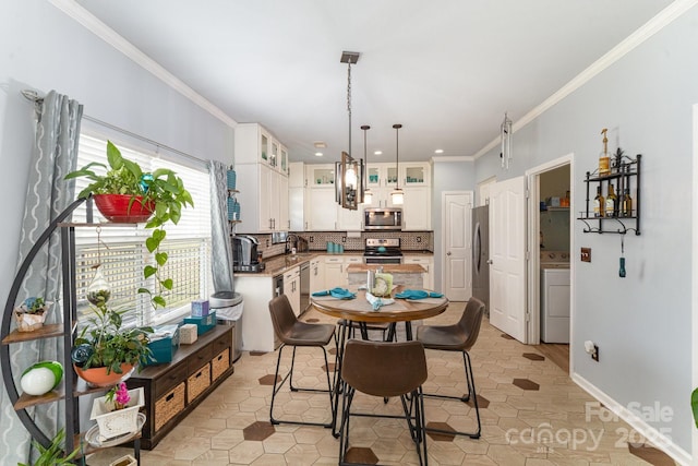 dining area featuring baseboards, light tile patterned flooring, ornamental molding, and washer / clothes dryer