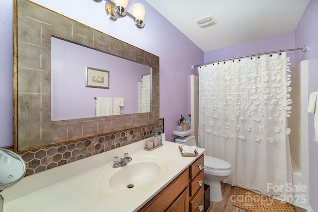 bathroom with vanity, toilet, visible vents, and decorative backsplash