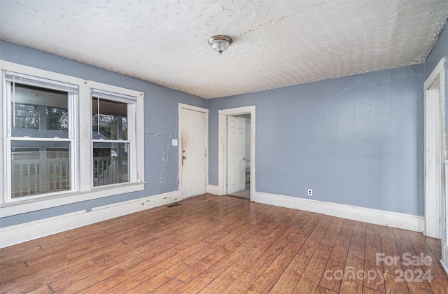 unfurnished room featuring wood-type flooring and a textured ceiling