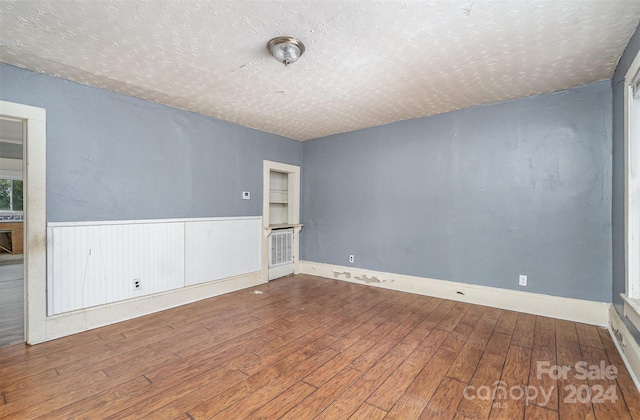 empty room featuring wood-type flooring and a textured ceiling