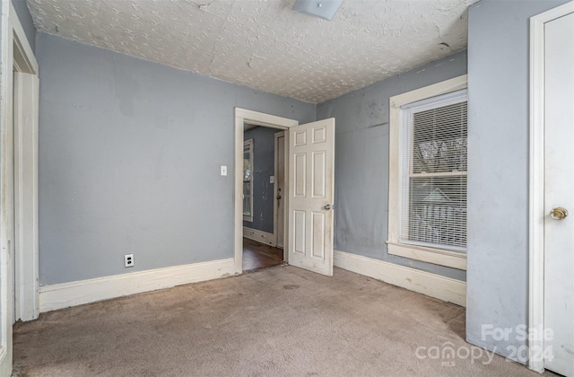 spare room with a textured ceiling and light colored carpet